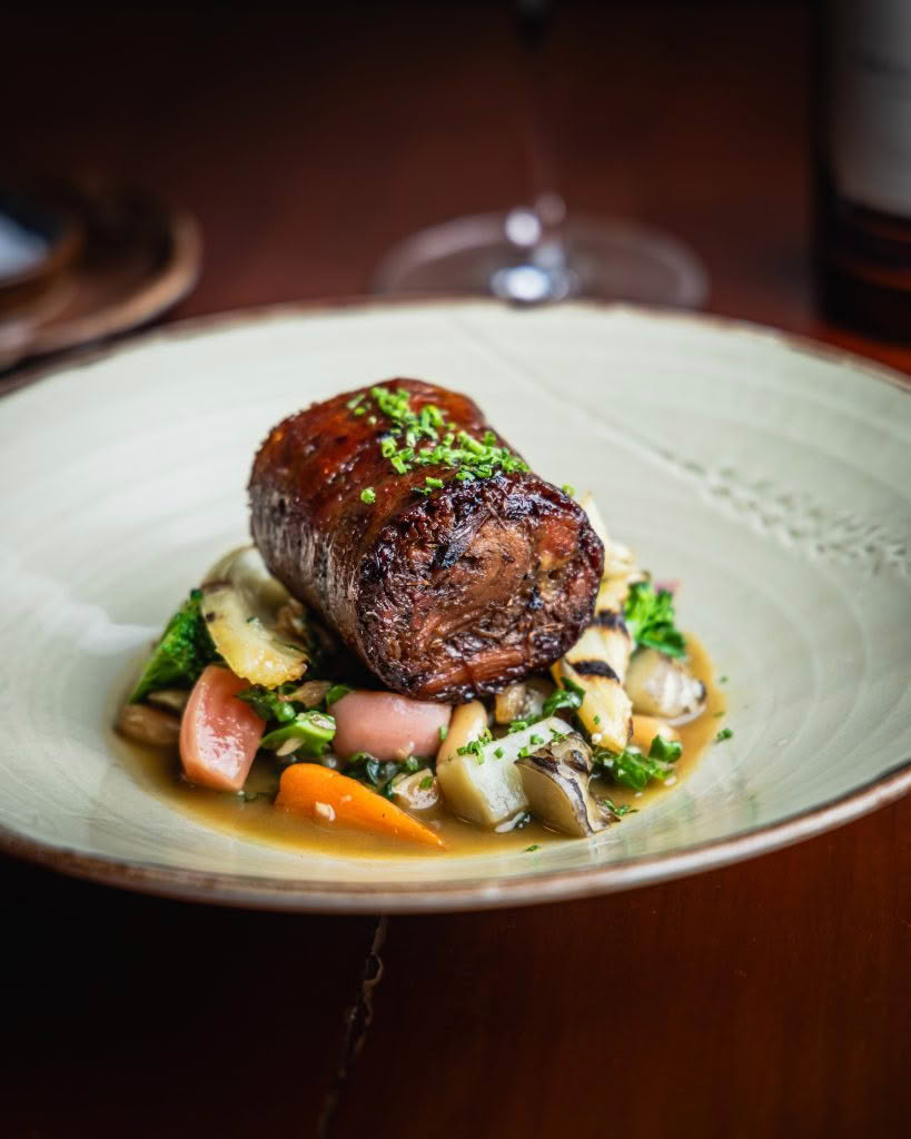 Cuisine Good Food Guide 2026 The Bistro Bacon Wrapped Lamb Shoulder, Cannellini Beans, Petite Vegetables, Anchovy Caramel
